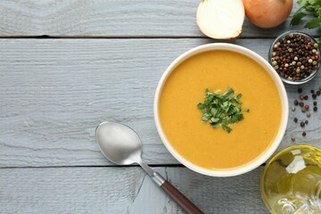 Delicious lentil cream soup with parsley served on grey wooden table, flat lay. Space for text