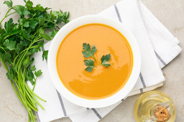 Delicious lentil cream soup with parsley and oil on light grey table, flat lay