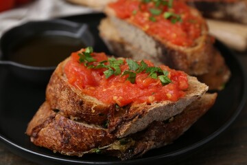 Tasty bread with tomato, parsley and oil on table, closeup