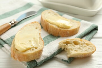 Slices of bread with butter on white wooden table, closeup