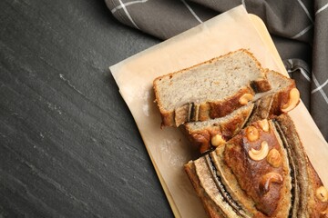 Cut banana bread with nuts on black table, top view. Space for text