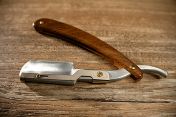 Old fashioned straight razor on wooden surface