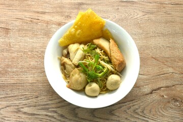 dry boiled Chinese yellow egg noodles dory fish and fishball with bean sprout topping crispy dumpling on bowl