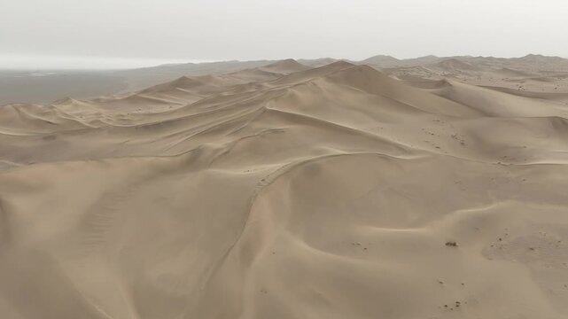 Drone flying on the sand dunes of The gobi desert with a gray misty sky in Gansu Province, China