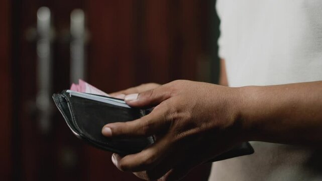 Close-up view of hand man gets out of the wallet 100 thousand rupiah cash banknotes and counts them. Payment and purchase concept.