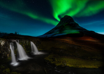 Kirkjufell, Iceland’s iconic mountain, stands beneath vibrant northern lights, with Kirkjufellsfoss waterfall cascading gently. This  Snæfellsnes Peninsula scene captures nature’s magical beauty. © LeeSensei