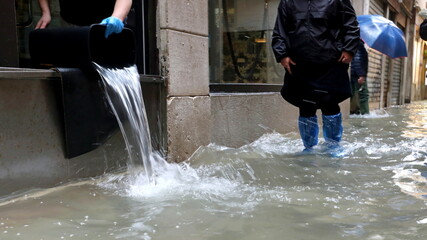 person emptying sea water from shop during high tide event in Venice northern Italy © ChiccoDodiFC