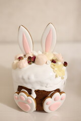 Easter cake decorated with white icing, almonds, meringues, dried roses, and bunny-shaped cookies with ears and paws. A festive and adorable holiday dessert perfect for spring celebrations.