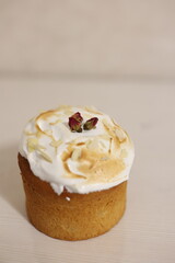 Homemade Easter cake with white meringue glaze, decorated with almond flakes and dried rosebuds. Traditional holiday pastry on a light background in a minimalist style.