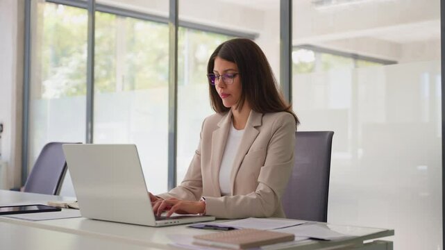 Young professional it specialist latin hispanic business lady working on laptop pc sitting at desk in modern office space. 30s middle eastern indian woman using computer technology app for work online - Powered by Adobe
