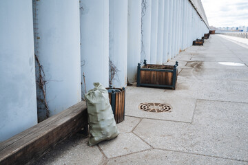 On the sidewalk, a bag is currently resting right next to a bench where people often sit and wait,...