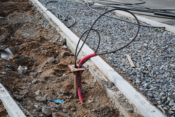 A bunch of various wires are protruding from the ground, jumbled together and creating an...