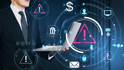 Businessman holding laptop with cyber threat warning icons and digital interface on dark tech background illustrating cybersecurity concept.