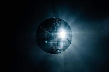 Disco ball in a dark room with smoke. Bright rays from a disco ball. Party, style and decor concept.