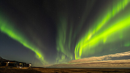 Aurora Borealis in Island, hellgrünes Polarlicht tanzt über den Nachthimmel, durch den Vollmond...