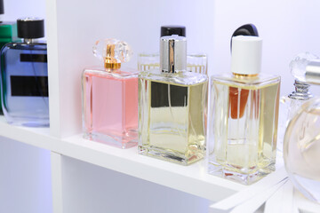 Different bottles of luxury perfume and fragrance blotters on shelf in store, closeup