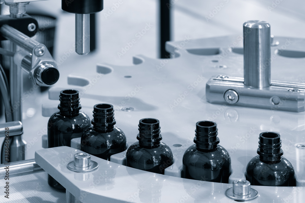Fototapete machine makes bottles with a black cap. there are five bottles in the process. the bottles are produ