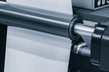 A machine is weaving a piece of fabric. The machine is made up of many parts, including a large metal piece that is connected to a hose