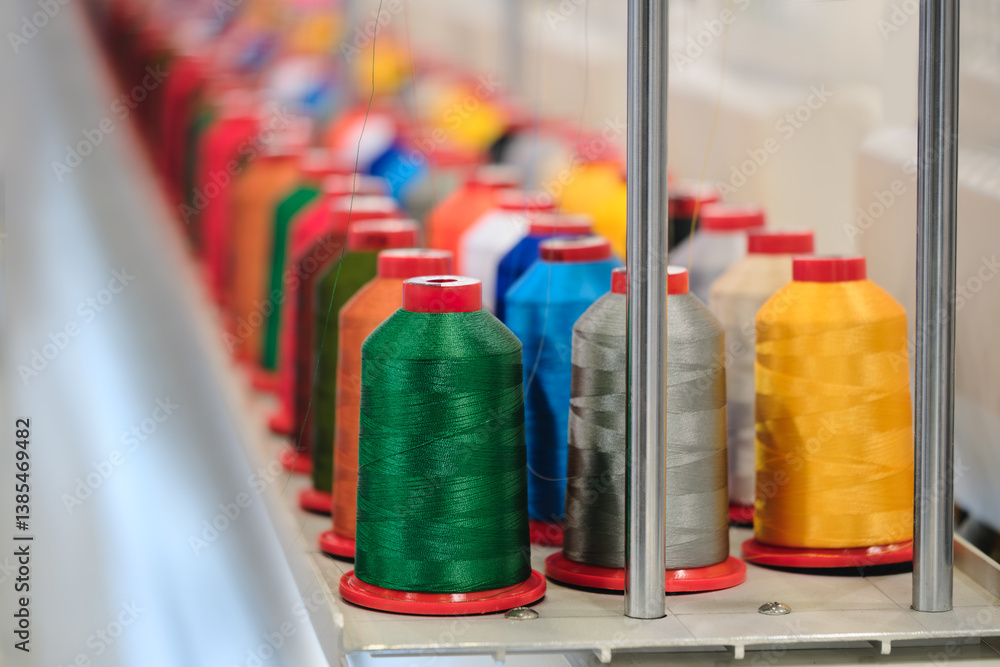 Poster A row of colorful spools of thread are on a table. The spools are of different colors and sizes, and they are arranged in a neat row. Concept of organization and order