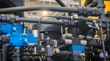 A machine with many pipes and valves. The valves are blue and yellow. The machine is in a factory