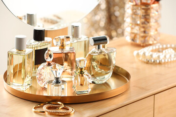 Different luxury perfumes on wooden dressing table indoors
