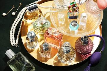 Different luxury perfumes and accessories on green pouf, above view