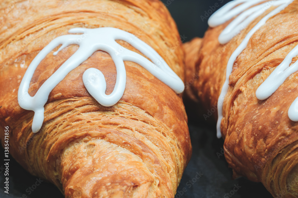 Poster two croissants with white icing on top. the icing is spread out and not too thick