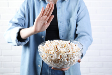 Woman refusing to eat popcorn near white brick wall, closeup. Food allergy concept