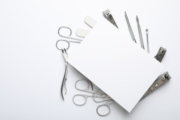 Set of different manicure tools and blank card on white background, flat lay. Space for text