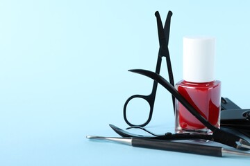 Set of different manicure tools on light blue background, closeup. Space for text