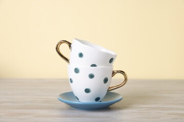 Beautiful cups and saucer on light wooden table against beige background