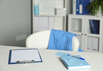 Doctor's workplace. Clipboard and other stationery on white table in medical office