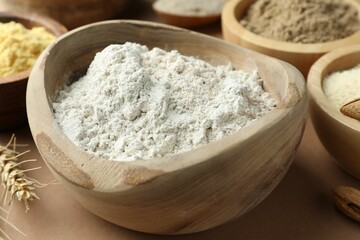 Different types of flour on light brown table, closeup