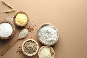 Different types of flour on light brown table, flat lay. Space for text
