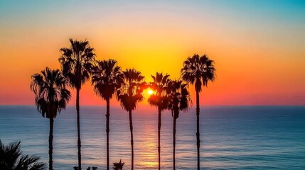 Fototapeta premium Silhouetted palm trees meet a golden sunset horizon over the ocean, capturing a moment of tranquility on the coast.