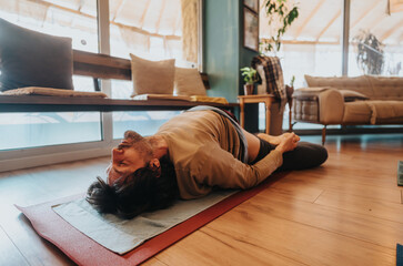 A man performs a yoga pose on a mat indoors, in a cozy and comfortable living space, focusing on...