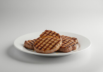 Grilled Meat Patties on a White Plate Against a Grey Background