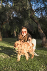 Woman shows affection to her cocker spaniel in a sunny park on a peaceful day