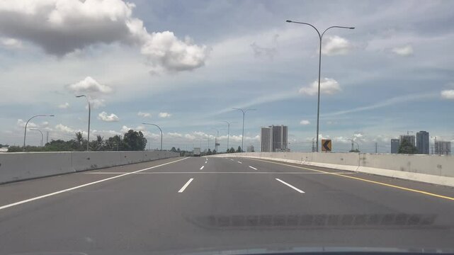 Dashcam view driving a car in Highway with Blue Sky and Building Skyline in Distance