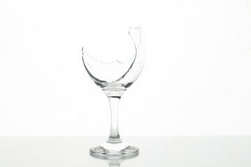 One broken wine glass on table against white background