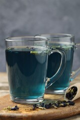 Delicious butterfly pea flower tea on wooden table against gray background