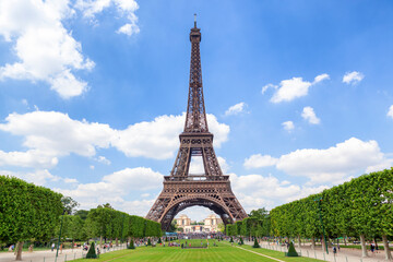The Eiffel Tower stands tall and majestic against a vivid blue sky, framed by symmetrical green lawns and trimmed trees.