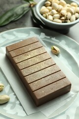 Tasty Dubai chocolate with pistachios and knafeh on grey table, closeup