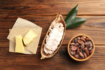 Cocoa pod with beans and butter on wooden table, flat lay