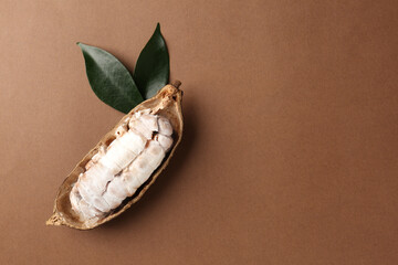 Cocoa pod with beans on brown background, top view. Space for text