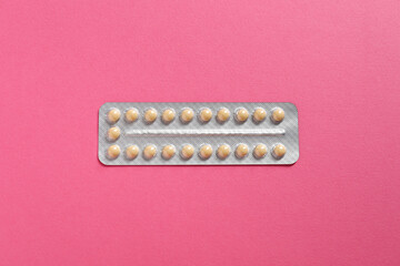 Blister of contraceptive pills on pink background, top view