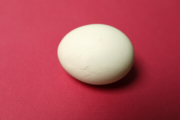 One egg with cracked shell on pink background