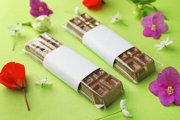 Delicious Dubai chocolate bars and flowers on green background, closeup