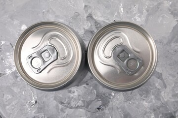 Obraz premium Refreshing drinks in cans on ice cubes, top view