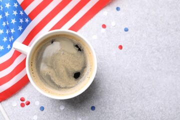 Cup of coffee, confetti and American flag on light table, flat lay. Space for text